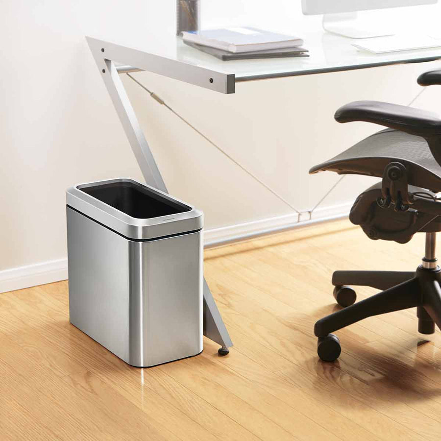 Lifestyle view of Simplehuman 25L Slim Open Can Brushed Stainless Steel under desk, space-saving.