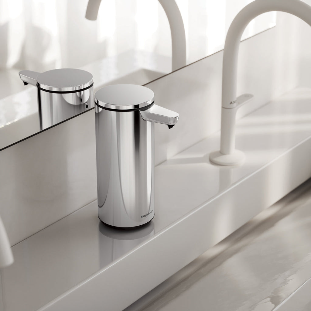 Simplehuman 9 oz. Sensor Pump, Polished Stainless Steel, on a modern white counter ledge, touch-free operation.