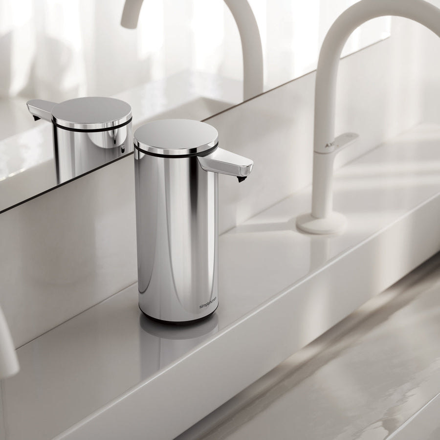 Simplehuman 9 oz. Sensor Pump, Polished Stainless Steel, on a modern white counter ledge, touch-free operation.