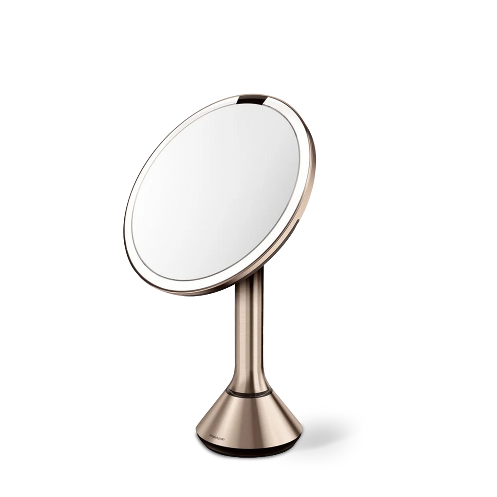 Angled view of Simplehuman Rose Gold Sensor Mirror Round with touch-control brightness and dual light setting.