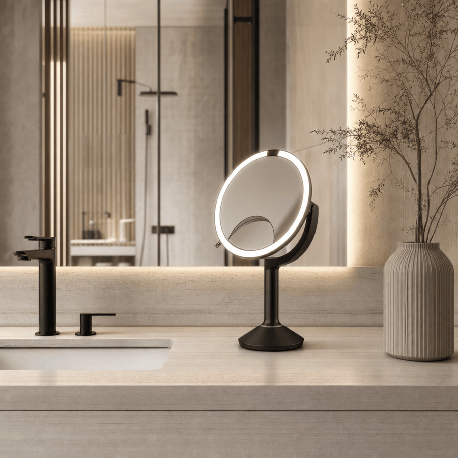 Simplehuman's Sensor Mirror Trio in Matte Black in a modern, upscale bathroom setting with matching matte gold appliances. 