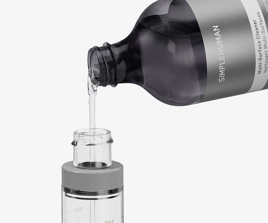 Simplehuman's Paper Towel Holder with Spray cartridge being filled with Simplehuman's Multi-Surface Cleaner Refill Bottle. 
